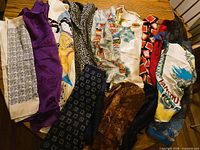 All 14 scarves spread out showing variety of colours and patterns