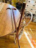 Four items on wooden floor: three canes and umbrella