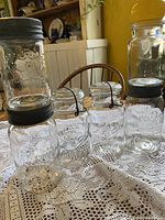 Five of the six jars displayed on lace cloth, showing varying lid types