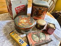 Group of seven tins and one retail box displayed on table