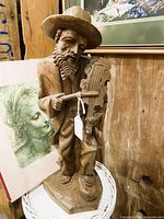 Front view of carved wood violinist statue on base