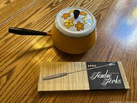 Fondue pot with lid and boxed forks on tabletop