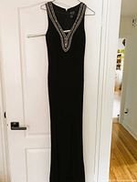 Full view of black sleeveless beaded gown hanging on door