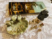 All items together on lace cloth: enamel tray, bird dish, Inuit carving, Wade figurines