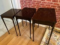 Three mahogany nesting tables standing side by side