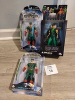 Three boxed Green Arrow action figures on floor showing fronts