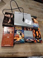 Top view of DVD player with cord and all five VHS tapes