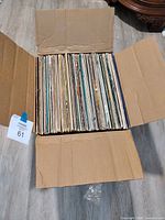 Open cardboard box showing spines of numerous 12" vinyl albums
