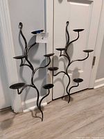 Front view of both wrought iron vine candle holders leaning against wall