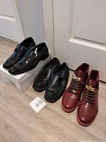 All three pairs of shoes lined up: Calvin Klein black patent loafers, George black loafers, Mecca burgundy sneakers