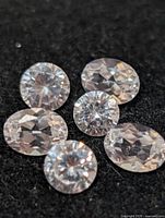 Six clear round faceted stones on black background