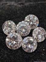 Six round brilliant cut cubic zirconia stones on dark surface