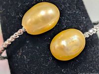 Close-up of two golden pearls on silver-tone band