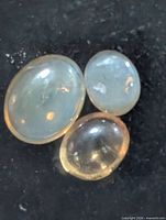 Three oval cat's eye cabochon gemstones on black background