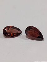 Two pear-cut garnet gemstones on white background