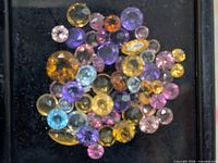 close-up of mixed loose gemstones inside display box