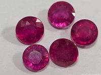 Five round faceted rubies on white background