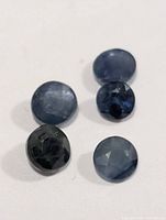 Five small round blue sapphires on white background