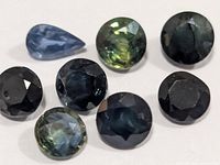 Nine loose faceted sapphires on white background