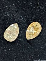 Both pear-cut fancy color diamonds on black background