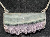 Close view of agate slice pendant with quartz crystals on silver chain