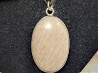 Front view of oval scolecite cabochon pendant in silver setting