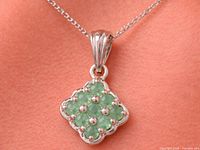 Front view of silver pendant on chain showing emerald cluster