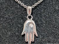 Close-up of silver Hamsa pendant with diamond