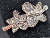 Front view of silver cubic zirconia ring with flower and butterfly design