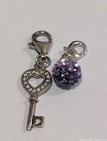 Key pendant with heart cutout and pavé stone ball pendant, front view
