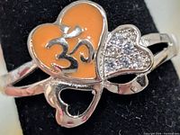 Front view showing orange enamel Om heart and CZ heart accents on silver ring