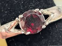 Close-up of garnet solitaire silver ring on display mandrel