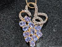 Front view of pendant showing tanzanite cluster and scroll accent