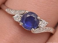 Close-up of silver ring showing sapphire centre stone, CZ side stones and pavé shoulders