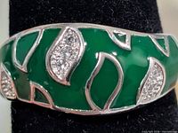 Close-up of silver ring with green enamel and CZ accents