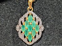 Front view of silver pendant with emerald cluster and halo of clear stones