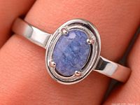 Close-up of sapphire set in sterling silver ring on finger