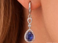 Earring on ear showing size, teardrop sapphire with accent stones and hoop