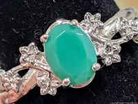 Close-up of green onyx cabochon and floral silver setting