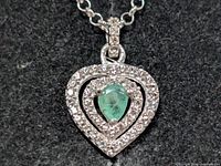 Close-up of emerald and CZ pendant on silver chain