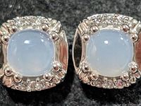 Close-up of both moonstone stud earrings showing stone color, metal setting, and accent details