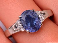 Ring on finger showing oval sapphire and accent stones