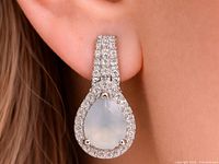 Close-up of one teardrop moonstone and CZ earring worn on ear
