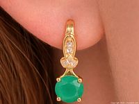 Earring worn on ear showing green onyx drop and clear accent stones