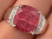 Front view of silver ring on finger showing dyed ruby and accent stones