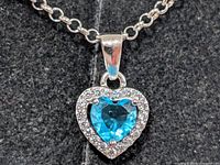 Close-up of heart blue topaz pendant with CZ halo on silver chain