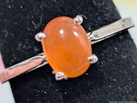 Front view of silver ring showing oval orange carnelian in four-prong setting