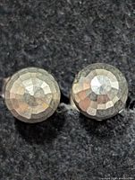 Close-up of two faceted silver ball earrings on dark background