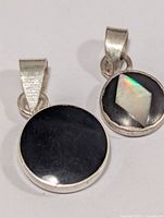 Front view of both silver pendants displaying stone faces