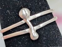 Front view of silver ring on display showing dual bands and bead bar